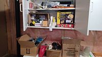 Wide shot showing upper cabinet and boxes on a shelf with various items including Wagner Power Painter Plus box.
