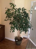 Full view of faux tree with planter in room corner showing height and foliage.