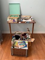 Overview of the lot showing a small table with a wooden-handled basket filled with yarn and miscellaneous craft items, boxes on the floor containing knitting and craft materials.
