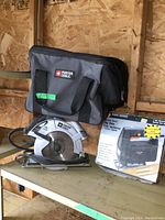 Porter Cable circular saw, carrying bag, and boxed Black & Decker jigsaw displayed on wooden shelf.