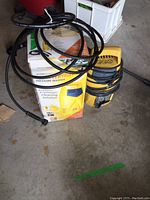 Pressure washer unit with hose and wand coiled on top, alongside original box