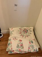 Folded quilt showing rose and cream floral patterns and part of the scalloped edges.
