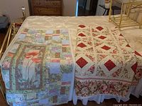 Two textiles on a bed: left wall hanging with floral poppy centerpiece and patchwork, right large quilt with red diamond pattern and floral border.