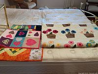 Quilt and three table runners displayed on mattress showing patterns and scale