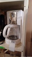 Oster coffee maker with glass carafe on shelf