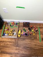 Overview of various toy cars of different sizes arranged on floor and in cardboard box.