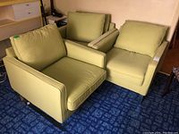 Three green fabric armchairs grouped together on blue patterned carpet.
