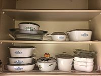 Full shelf with multiple CorningWare blue cornflower pattern vessels, Evesham covered pot, and glass lids