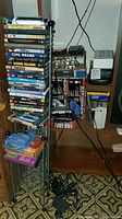 Full view of DVDs stacked on metal rack with other electronics behind