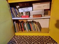 Shelf with vintage books, boxes labeled 'Building Bricks' and 'Train Set', and other boxed items.