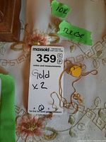 Chain and two pendants on floral background with MaxSold lot card showing gold x2 and karat labels