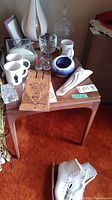 First side table viewed from front with various glassware and collectibles on top.