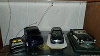 Front view of the blue GMC RC truck, black Cadillac model car, and classic convertible model car with antennas and controller visible.