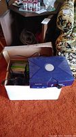 Top view of translucent blue Xbox console and box containing controllers and game cases