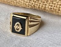 Front view showing square black onyx top with gold “O” emblem and ridged shoulder details