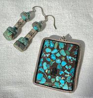 Earrings and pendant laid flat showing turquoise and silver details.