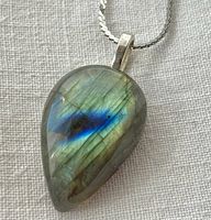 Close-up of the labradorite pendant showing teardrop shape, iridescent blue and green flashes, and natural stone patterns.