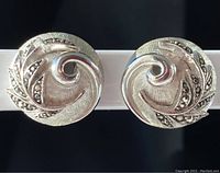 Front view showing silver-tone spiral design with marcasite leaf accents.