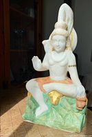 Front-left angle of the white marble Lord Shiva statue with colored and gold accents, showing seated posture and facial details.