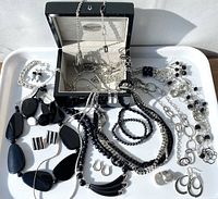 Photo showing a collection of black and silver costume jewelry including various necklaces, bracelets, earrings, and a jewelry box.