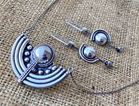Close-up of the necklace pendant and earrings laying on burlap fabric
