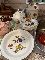 Photo showing four Royal Worcester Evesham Vale china pieces: tea pot, canister, serving dish, and plate with fruit motifs.