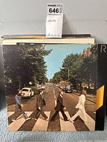 The Beatles Abbey Road album cover showing band members crossing the street on a crosswalk. Vinyl record in vintage used sleeve.