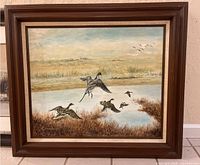 Frontal view of the signed painting of geese in flight within a wooden frame, showing the full artwork and frame.
