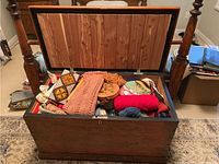 Photo of vintage wooden blanket chest opened, showing interior and some contents