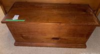 Front view of vintage wooden blanket chest showing the wood grain and patina on the surface.