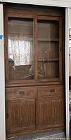 Full view of wooden hutch showing upper glass sliding doors and interior shelves.