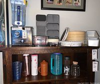 Image of the various kitchen items including water bottles, lazy Susan trays, pie dish, bamboo steamers, and metal pans arranged on a wooden surface.