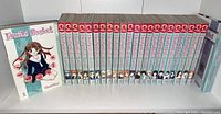 All 23 volumes lined up on shelf with binder of sticker collection at right