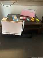 Dark wood desk organizer on a black surface with a desk calendar attached to the front and various office supplies on top and inside the compartments.