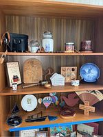 Wooden shelves holding collection of binoculars, decorative plates, candles, hot air balloon figurines and wall plaques