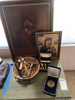 Overall lot with two framed religious artworks, religious jewelry with crosses, and Olympic medal on display table
