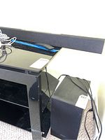 Samsung sound bar alongside Samsung subwoofer and remote on shelf.