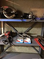 Metal shelf with the Ryobi circular saw, Black & Decker tool, pipe wrenches, staplers and heat applicator.