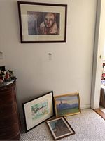 Four framed art pieces: one hanging on the wall and three on the carpet floor.
