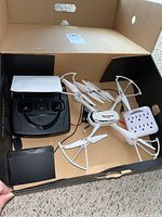 Photo showing the drone, black remote controller, user manual, and accessories inside a box.