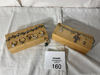 Display of sterling silver rings, bracelets, and pendants on wooden blocks and white fabric background.