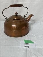 Full view of the antique copper kettle showing rounded body, spout, and wooden handle.