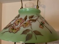 Close-up of the hand-painted floral milk glass shade with a small flea chip at its base.