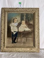 Front view of hand-colored Victorian photograph of two children in an ornate carved antique frame with visible wear and damage