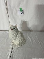 Front view of white ceramic Persian cat figurine with detailed fur, pink nose, blue eyes.