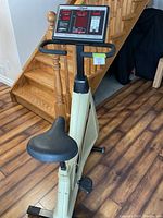 Front view of beige Lifecycle 6500 stationary bike with seat and pedals, black padded seat, handlebars, and base with floor leveling feet.