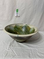 Side view showing the bowl's shape and painted interior pattern with green leaf motifs.