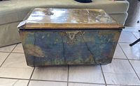 Front view of trunk showing brass-toned finish, embossed hardware and overall shape