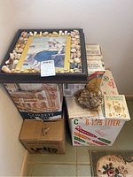 Photo of four boxes stacked with framed shell collection and book on top, showing overall lot contents and packaging.