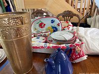 Full lot display with 25-piece dish set, two metal vases, and blue teapot on table